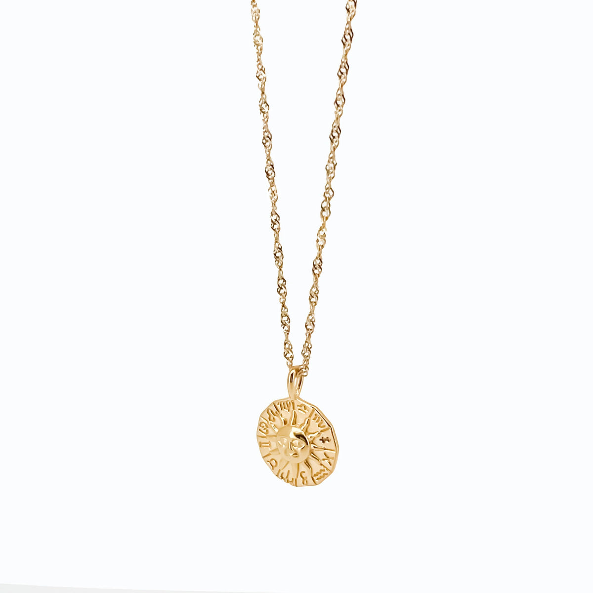 Gold medallion pendant on a delicate twisted chain necklace.
