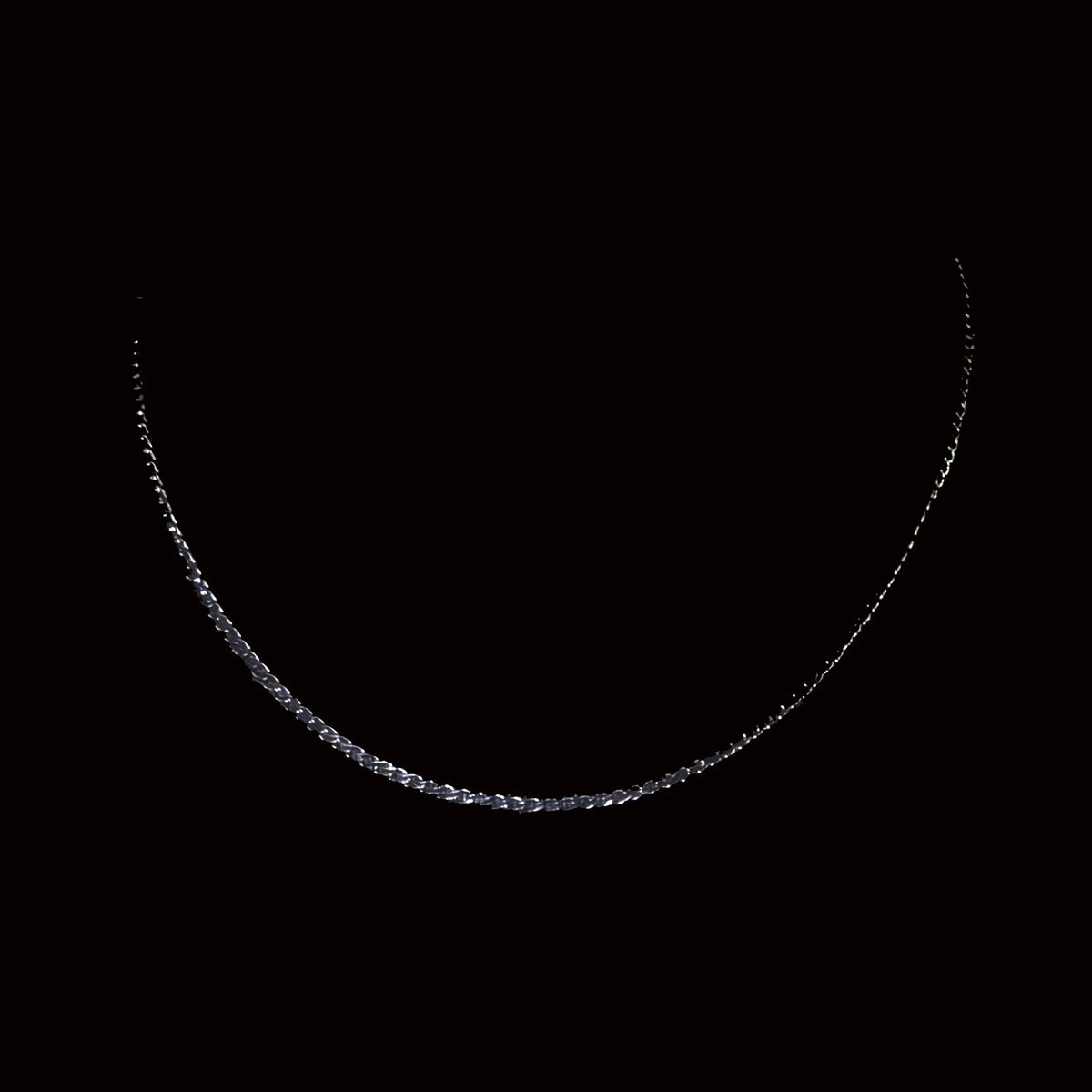 Delicate silver chain necklace against a dark background.