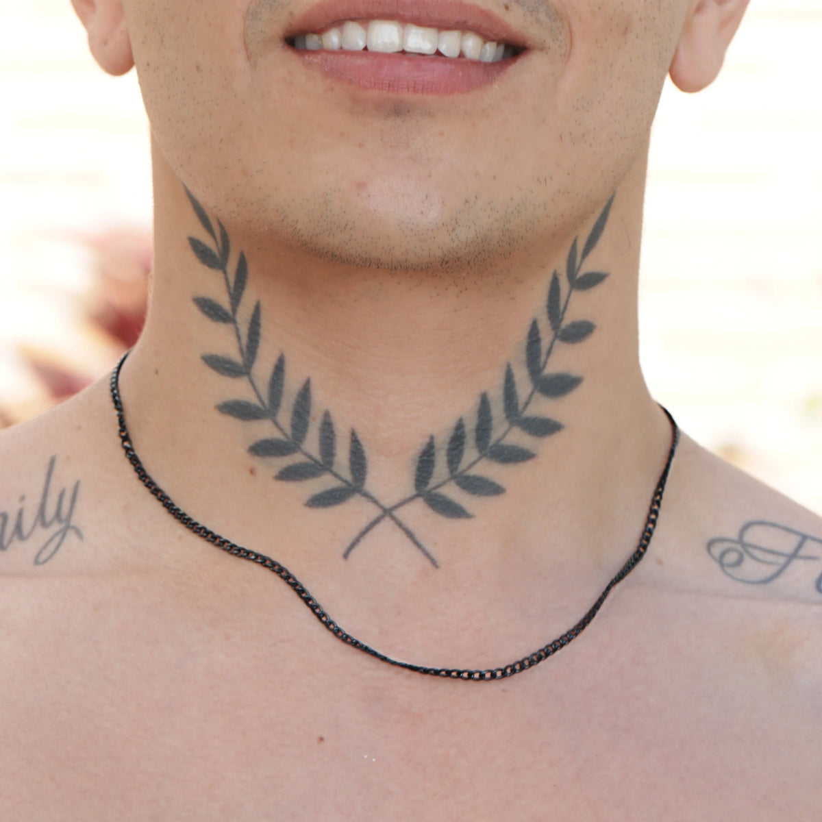 Tattoo of symmetrical olive branches on a neck.