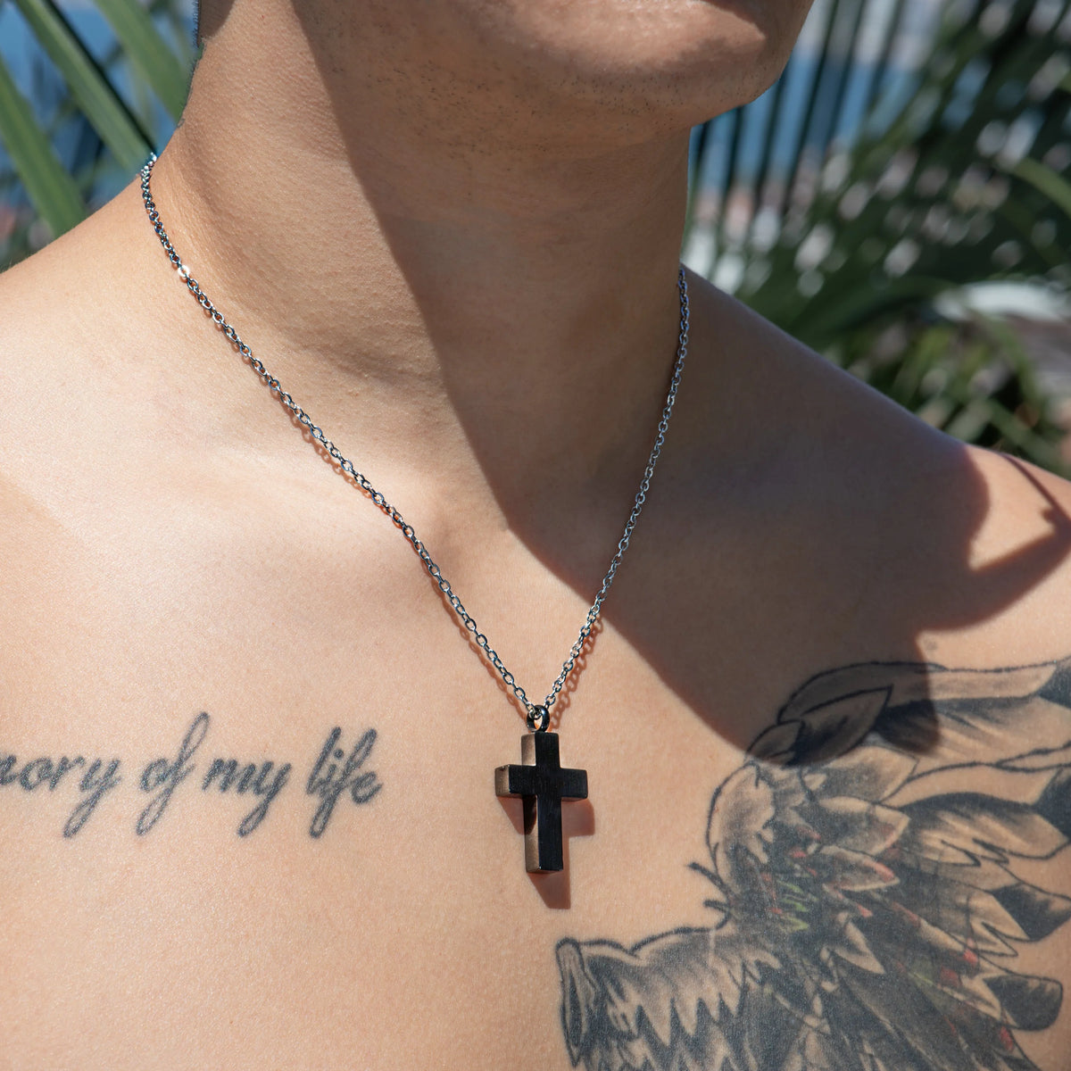 Silver necklace with a black cross pendant.