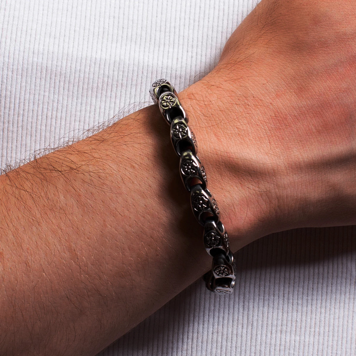 Black leather bracelet with metallic skull-shaped beads worn on a wrist.