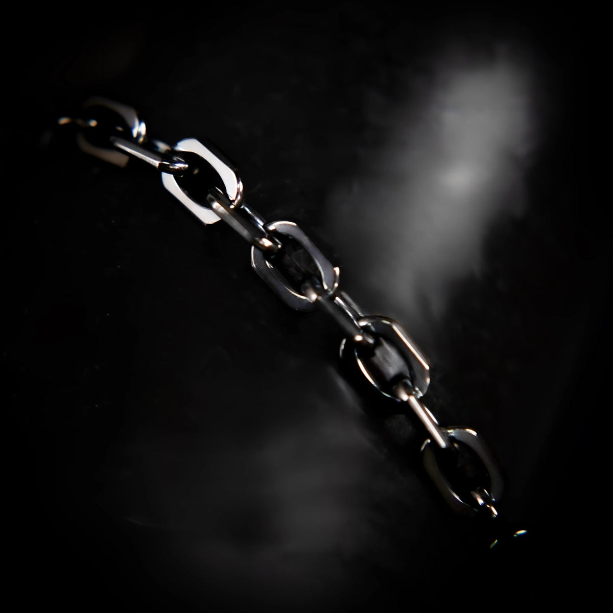 Metal chain with oval links against a dark background.