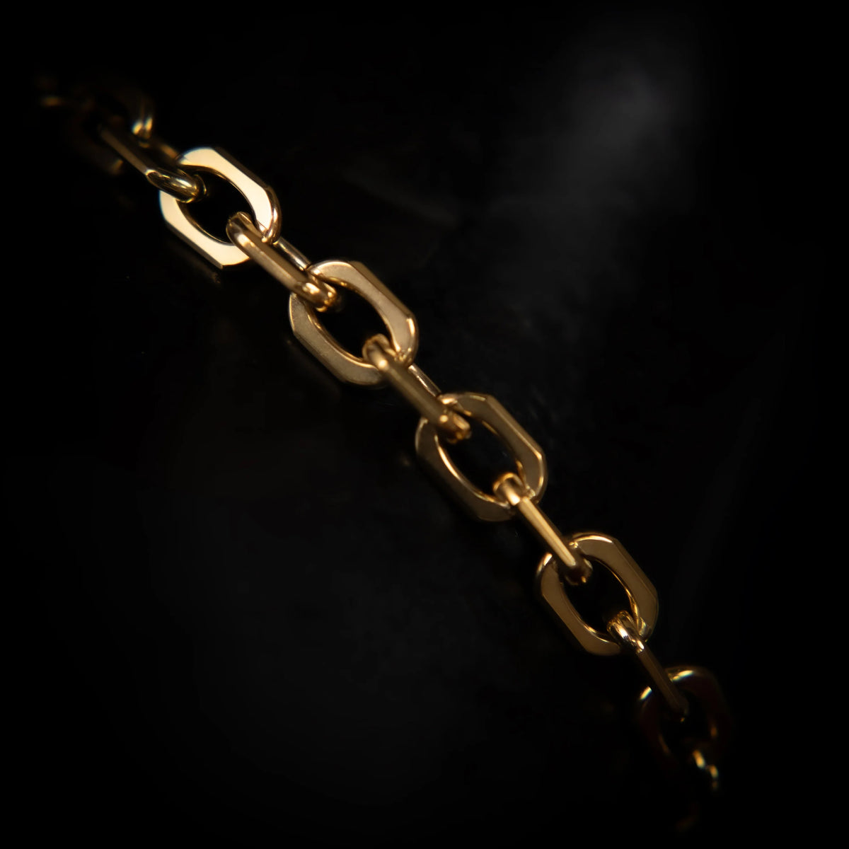 Gold chain with oval links against a dark background.