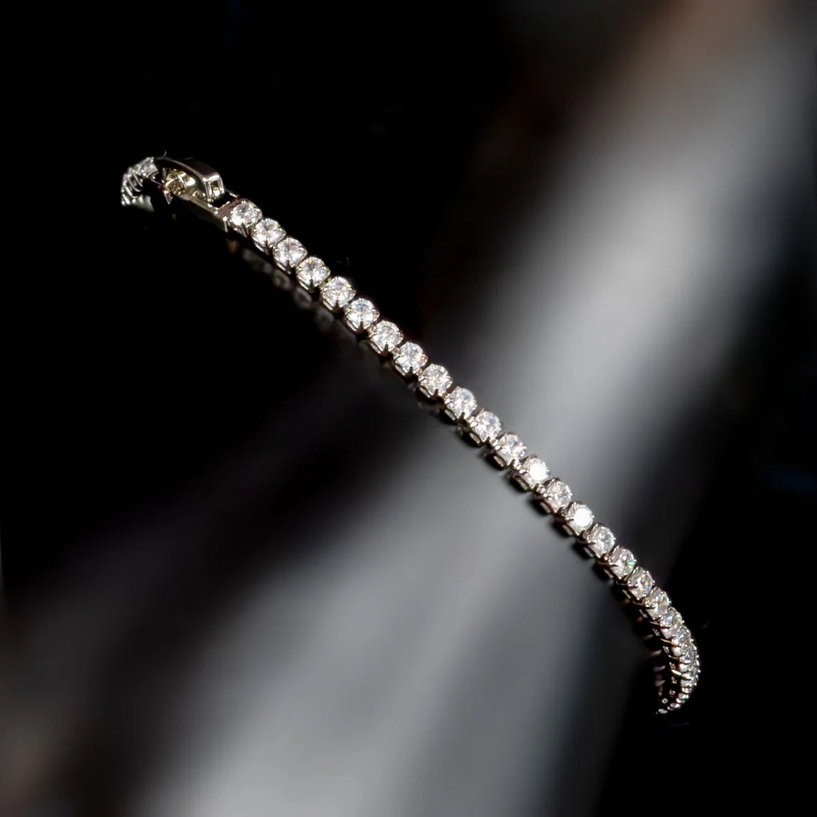 Diamond tennis bracelet with a row of sparkling stones set in a delicate metal band.