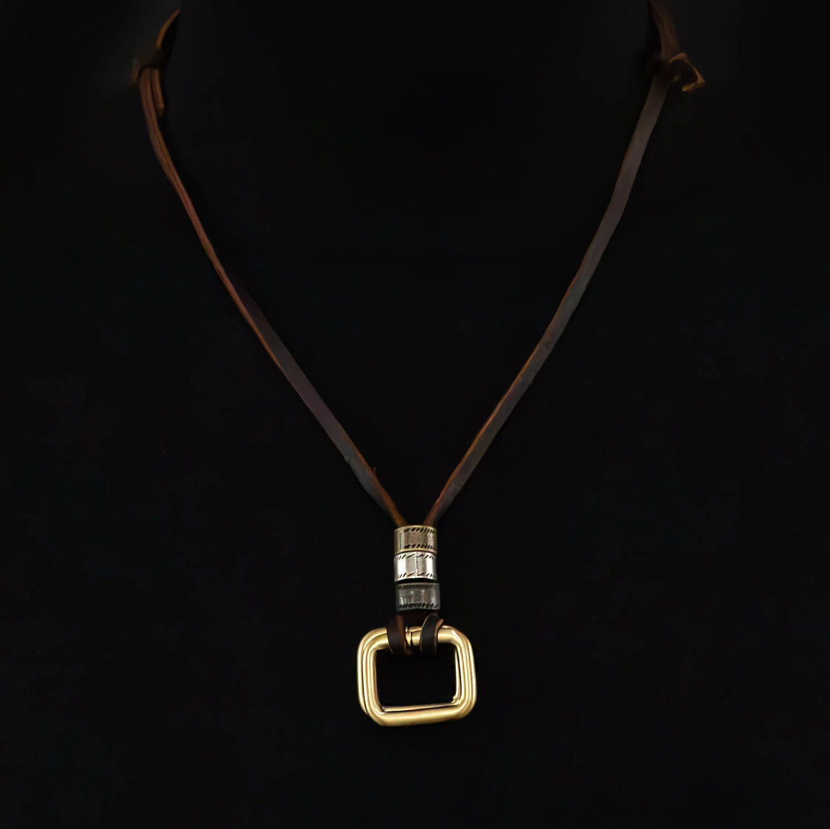 Necklace with a gold square pendant on a dark leather cord.