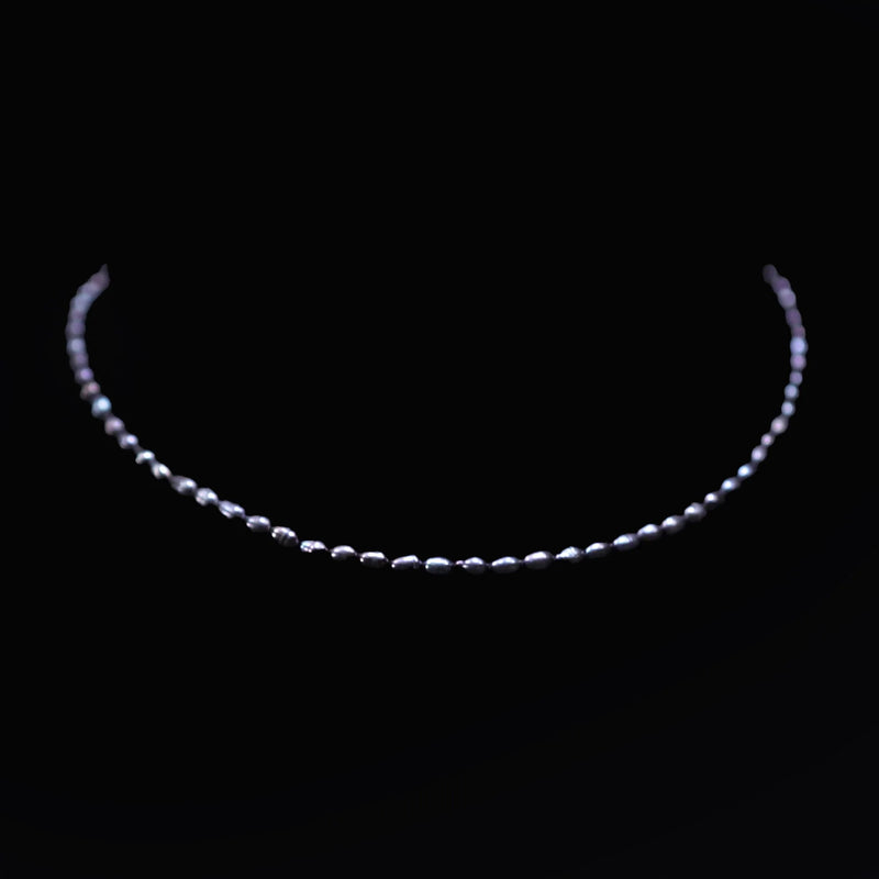 Delicate pearl necklace forming a curved arc against a dark background.