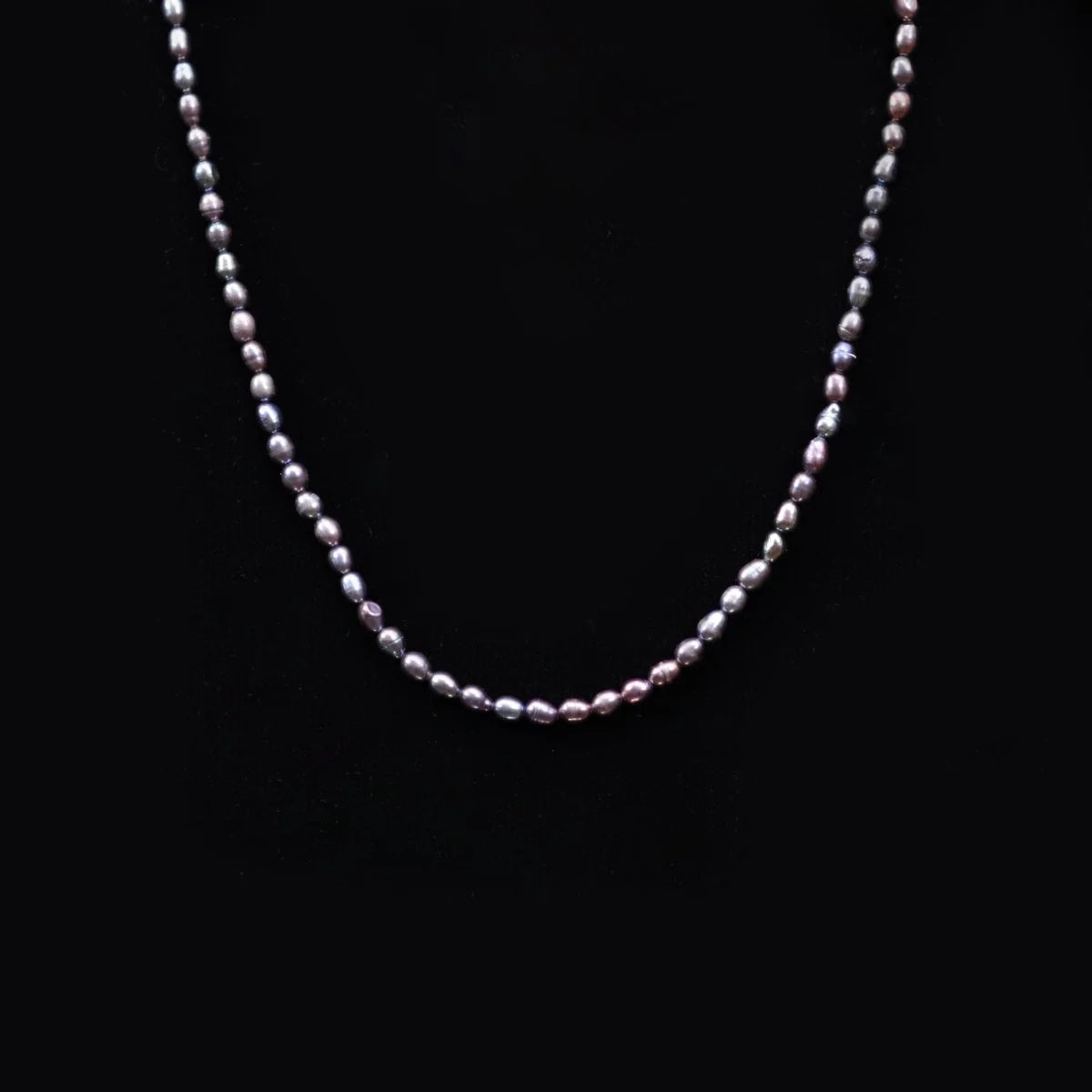 Pearl necklace with small, round beads on a dark background.