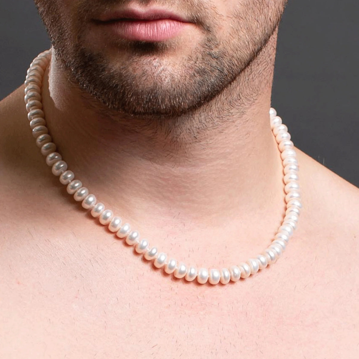 Pearl necklace worn around a man’s neck.