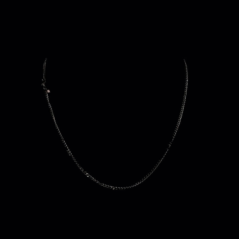 Simple silver chain necklace against dark background.