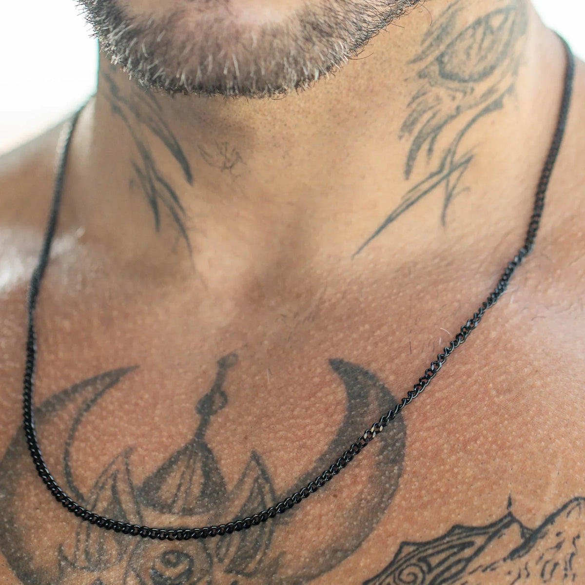 Black beaded necklace resting on tattooed skin.