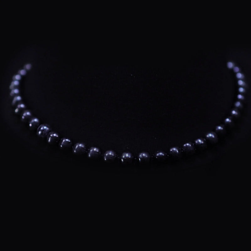 Pearl necklace arranged in a curved shape against a dark background.