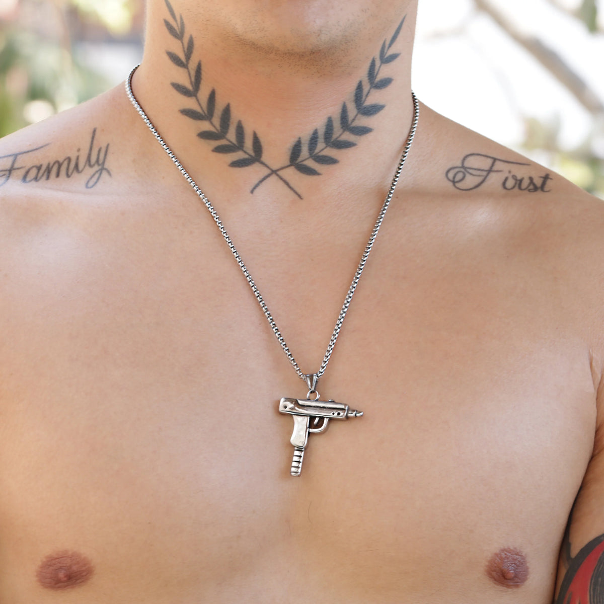 Silver necklace with a gun-shaped pendant.