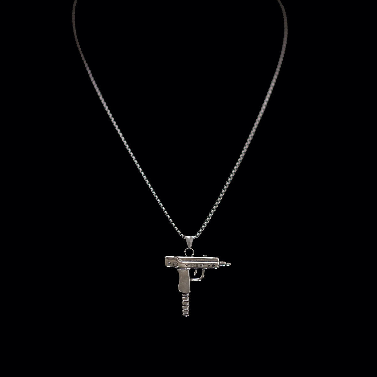 Silver necklace with a pendant shaped like an Uzi submachine gun.