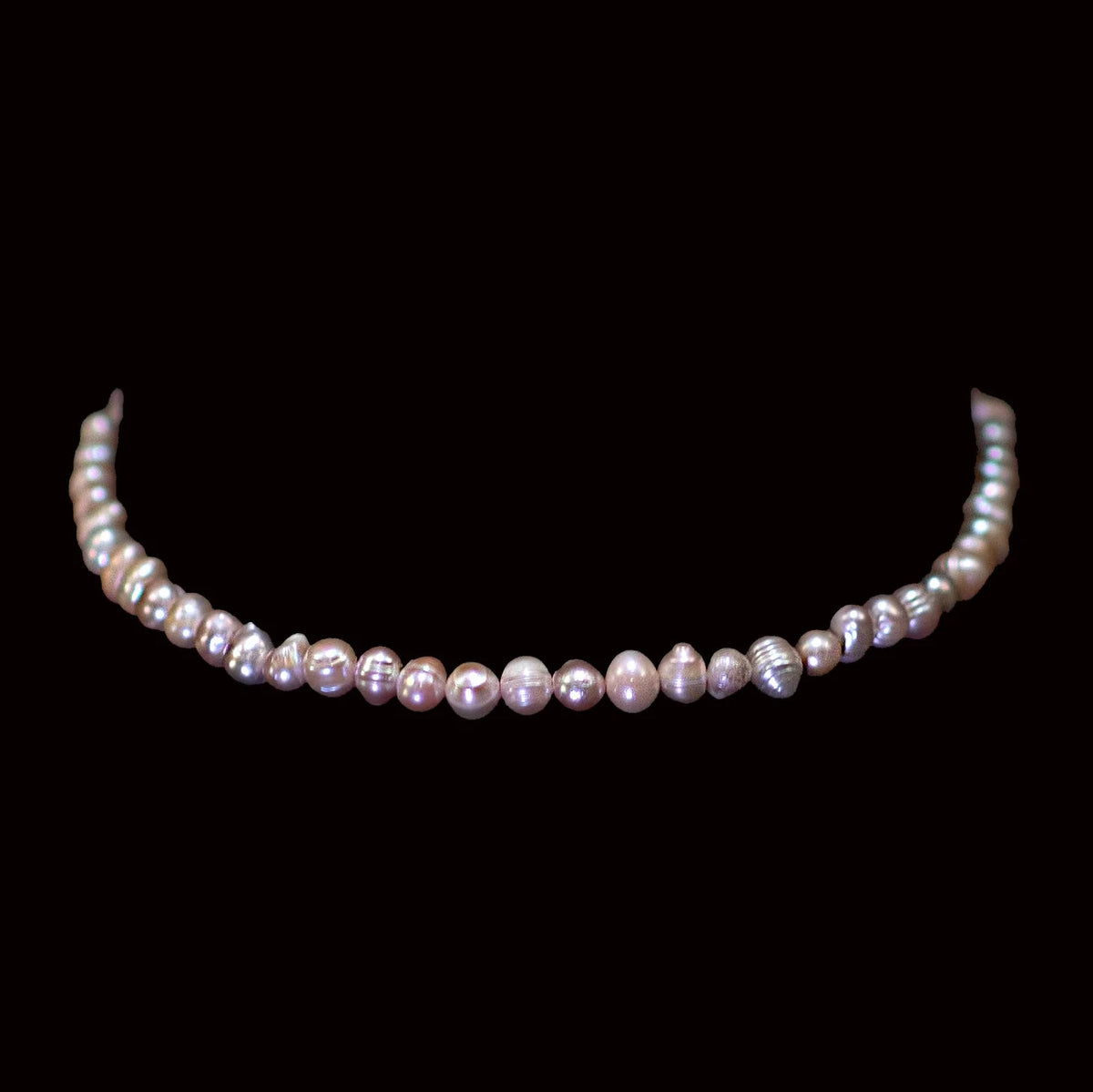 String of lustrous pink-toned pearls arranged in a curved necklace shape.