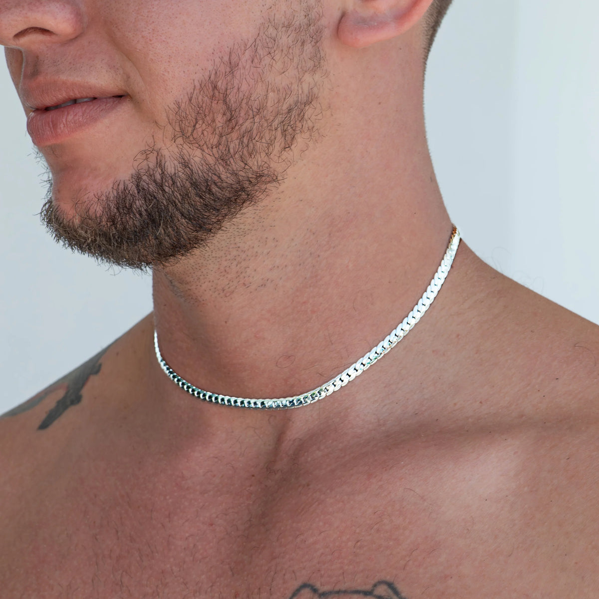 Silver chain necklace worn around a person’s neck.