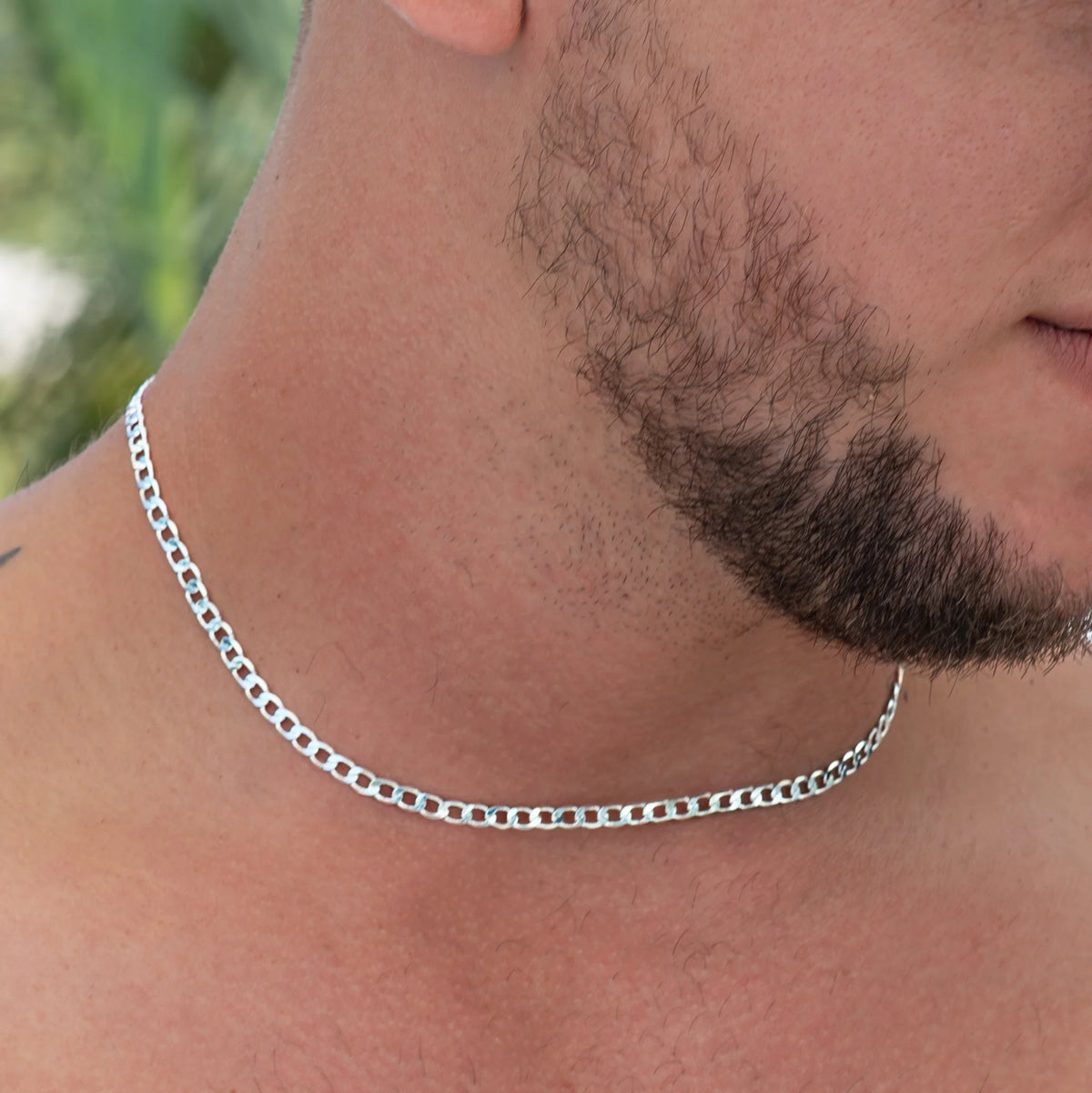 Silver chain necklace worn around a person’s neck.