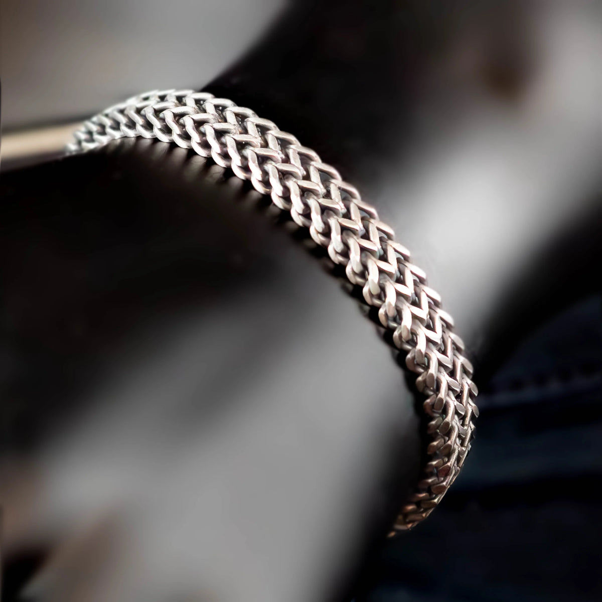 Intricately woven silver bracelet with a braided pattern.