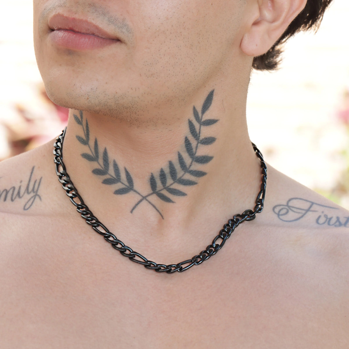 Tattoo of crossed laurel branches on a person’s neck.