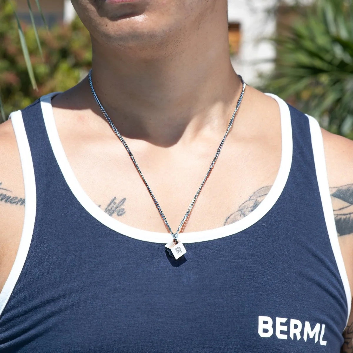 Navy blue tank top with white trim and ’BERML’ text, worn with a necklace.