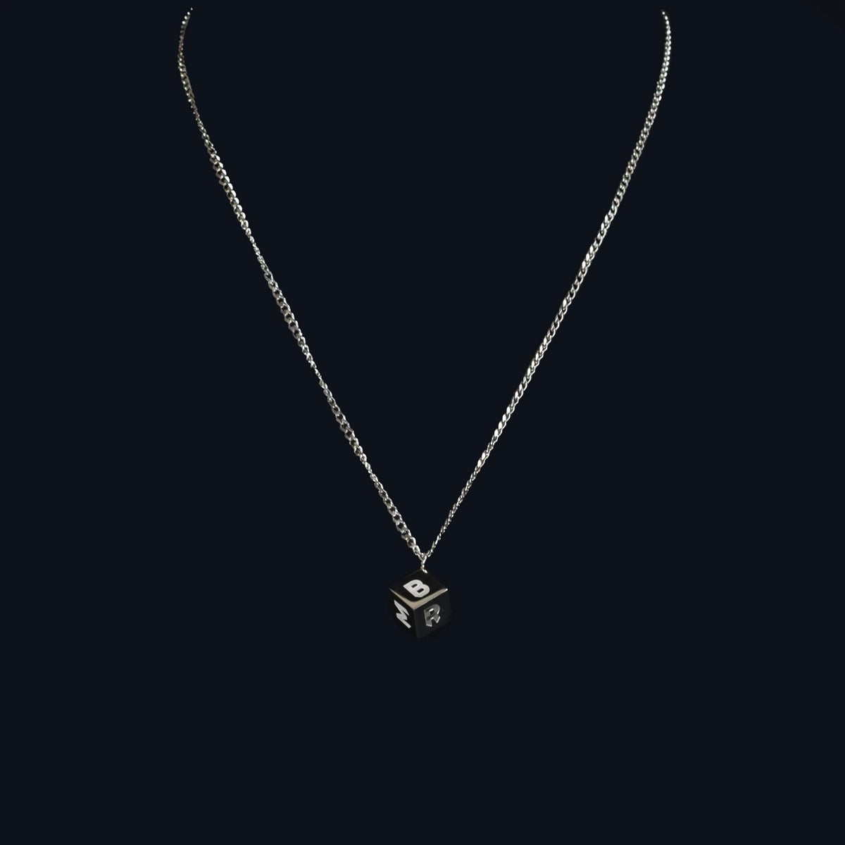 Silver necklace with a cube-shaped pendant.