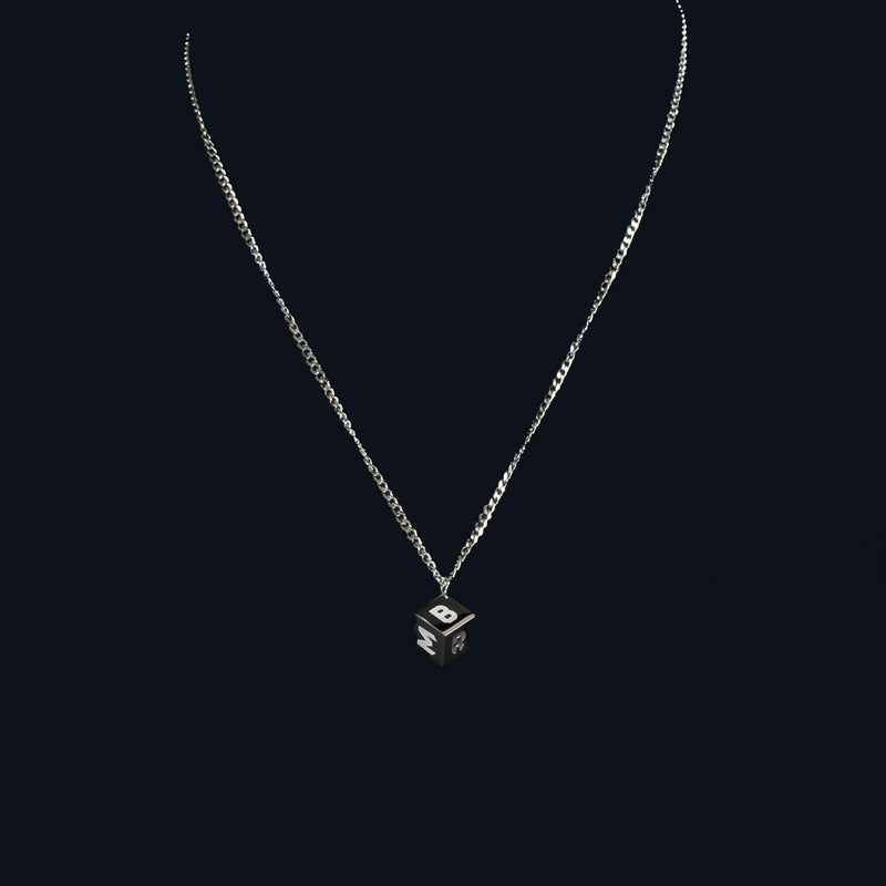 Silver necklace with a small cube-shaped pendant featuring an eye design.