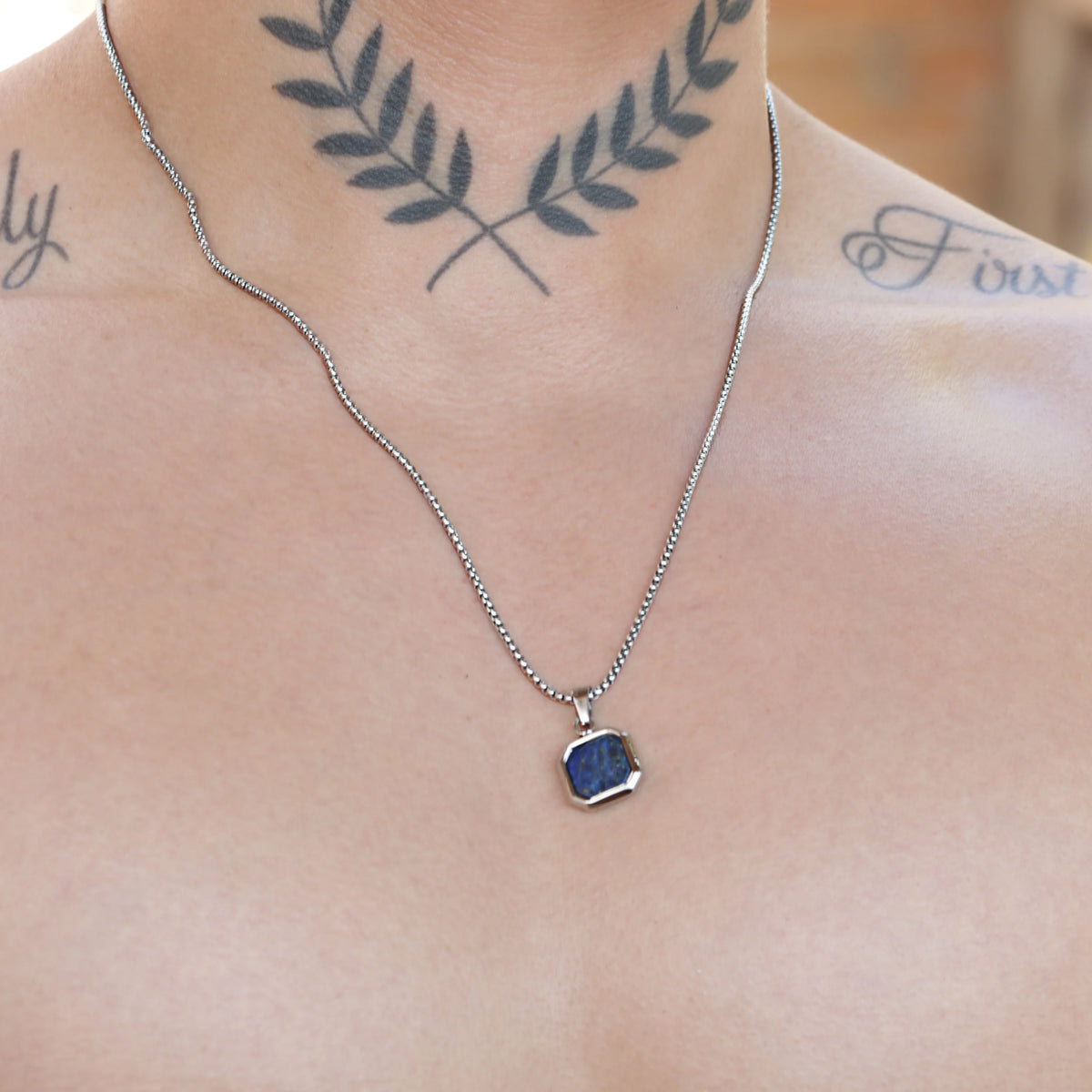 Silver necklace with a blue square pendant.