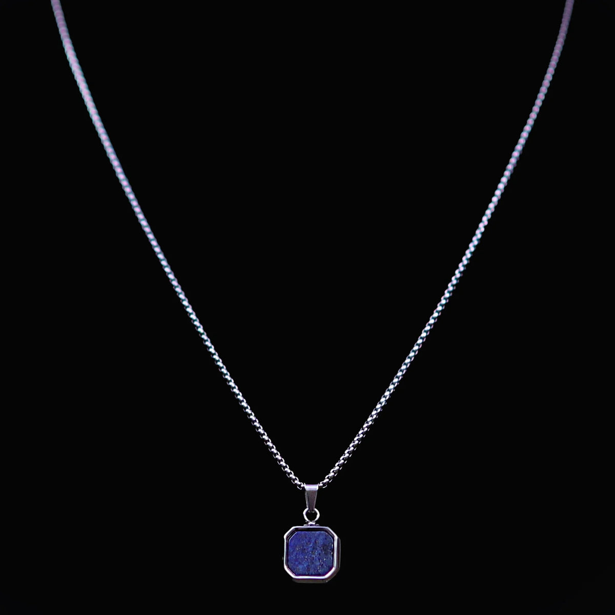 Silver necklace with a square blue pendant.