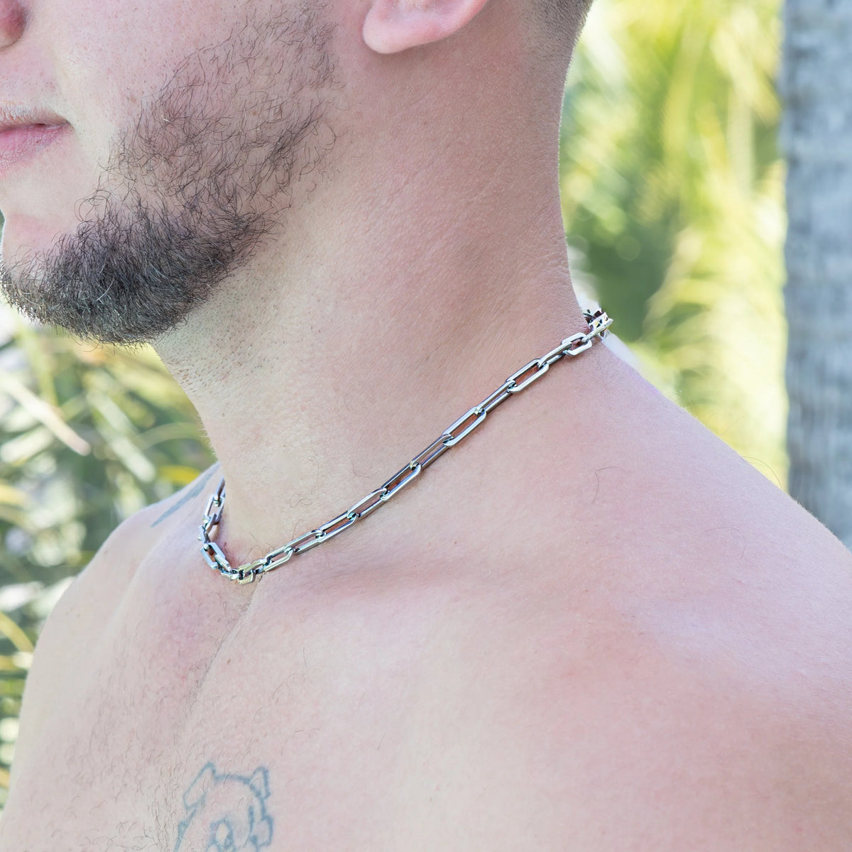 Silver chain necklace worn around a person’s neck.