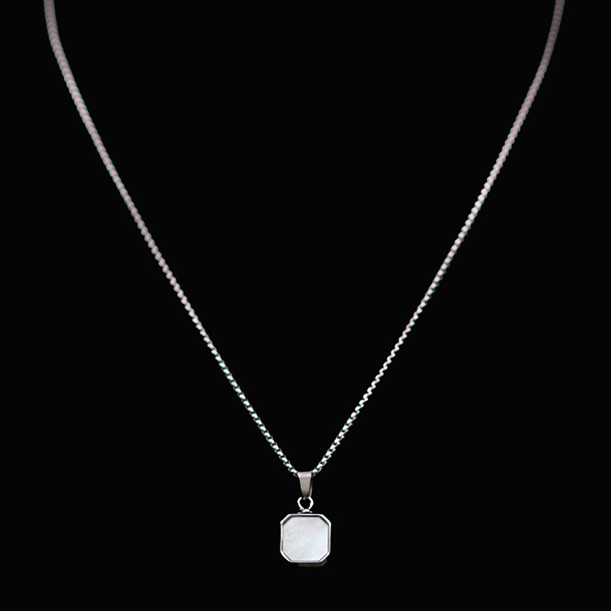 Silver necklace with a square pendant.