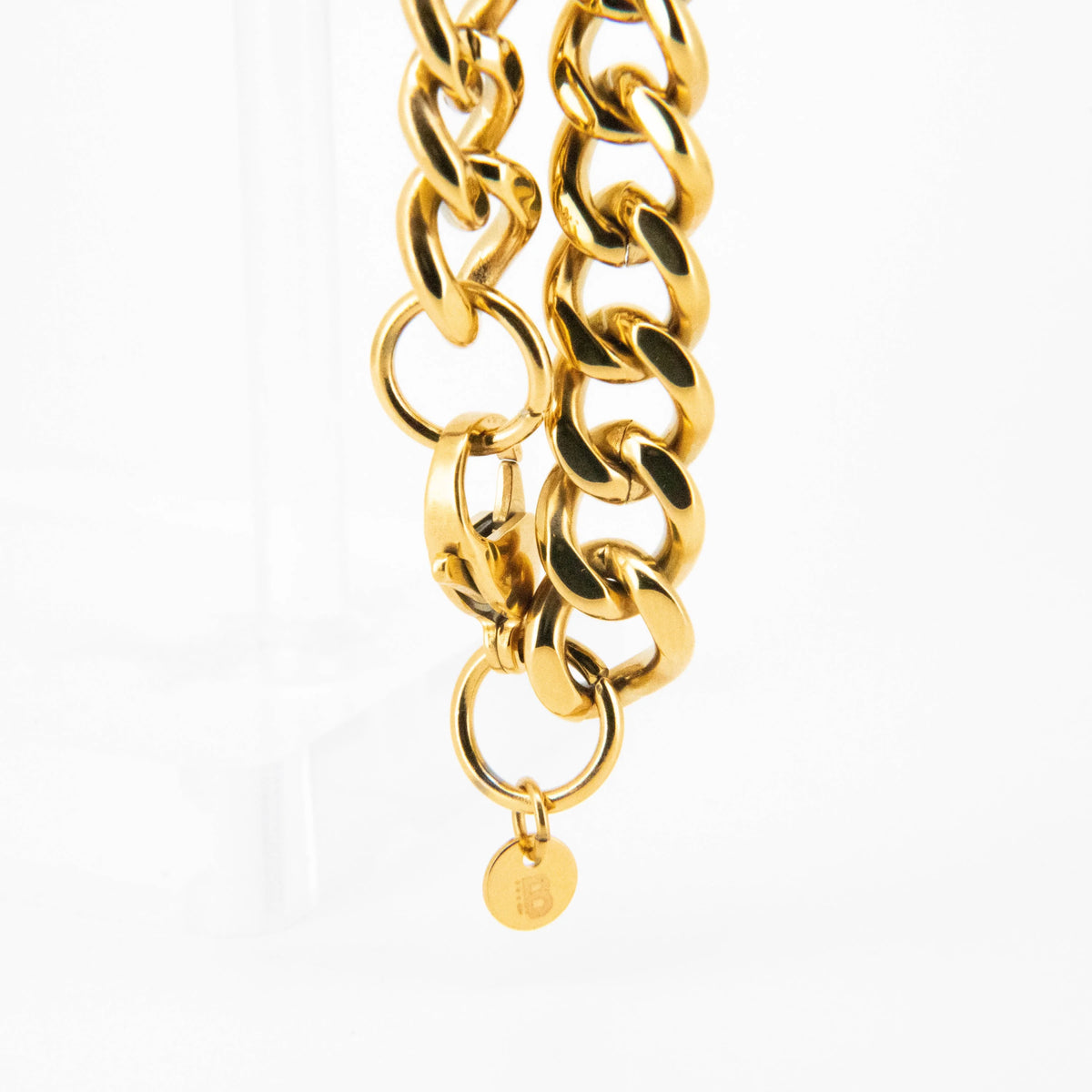 Gold chain bracelet with circular links and a hanging charm.