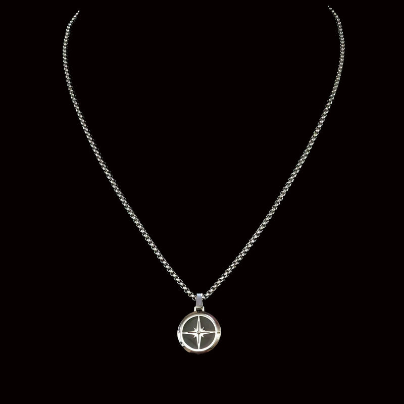 Silver necklace with a circular compass-like pendant.