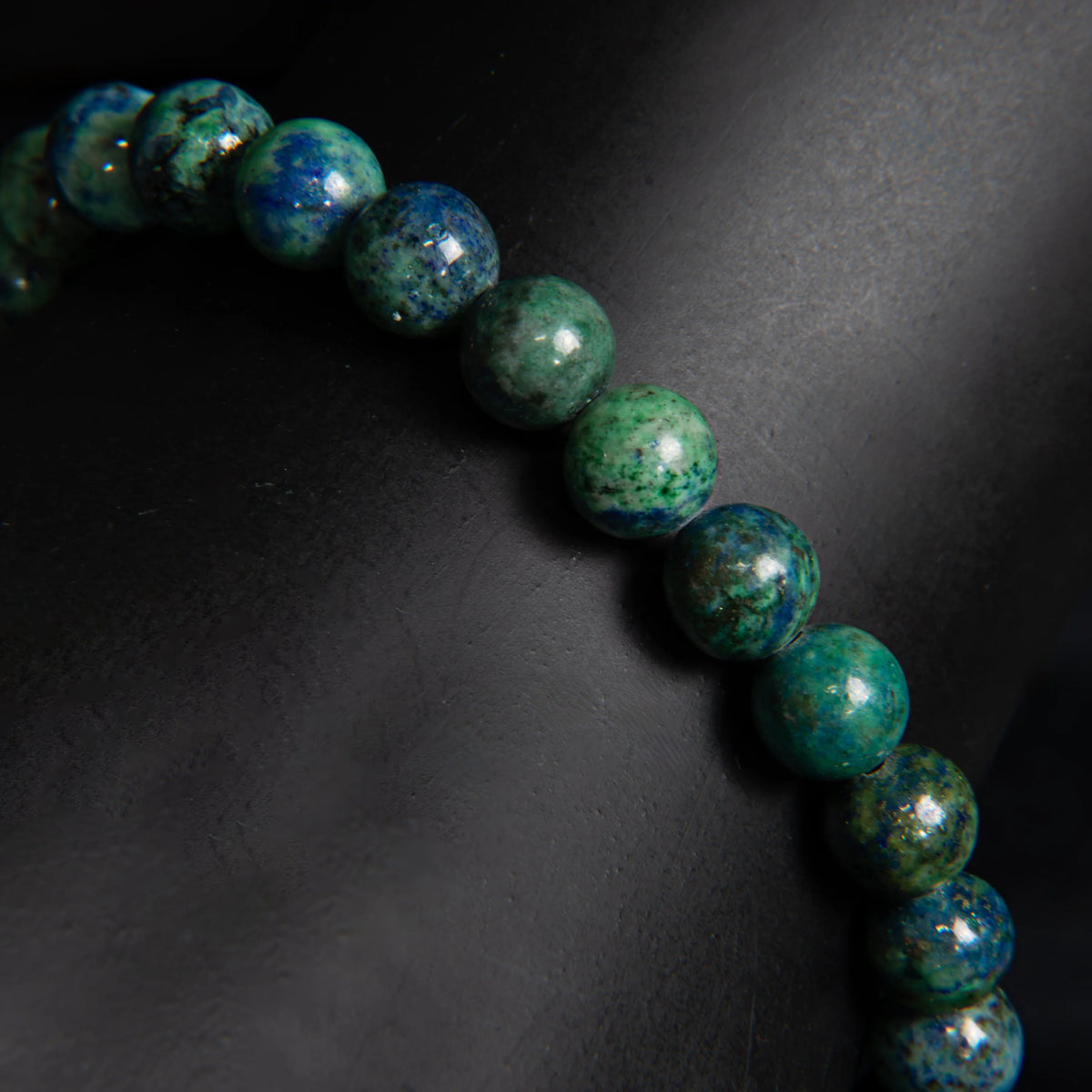 String of polished green and blue gemstone beads with a marbled appearance.