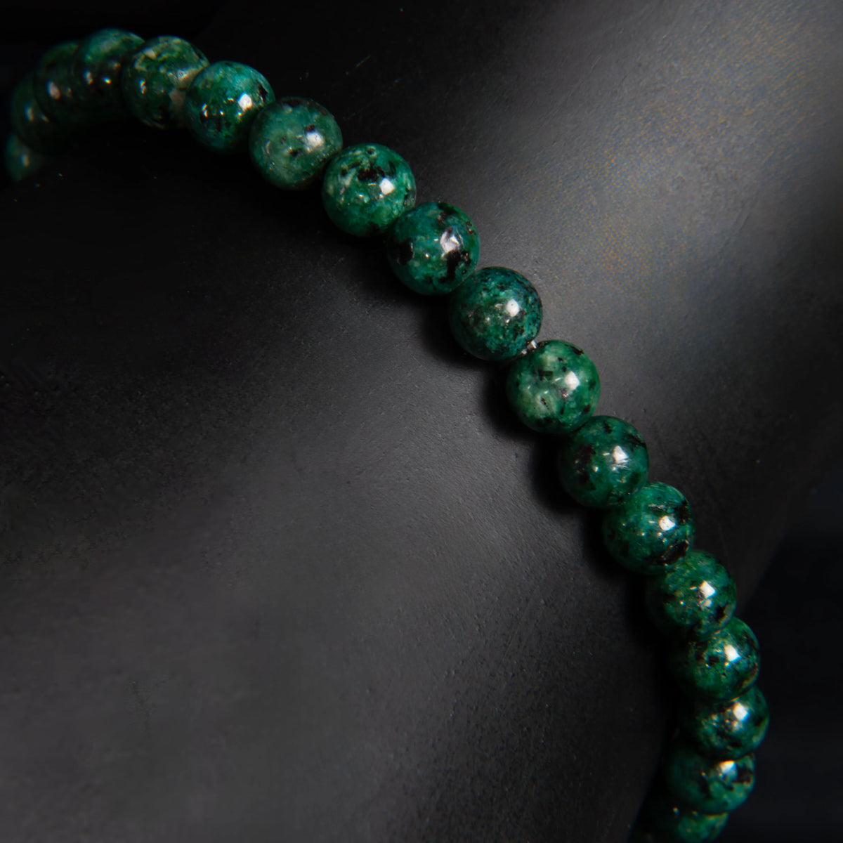 String of deep green, polished gemstone beads with a lustrous sheen.