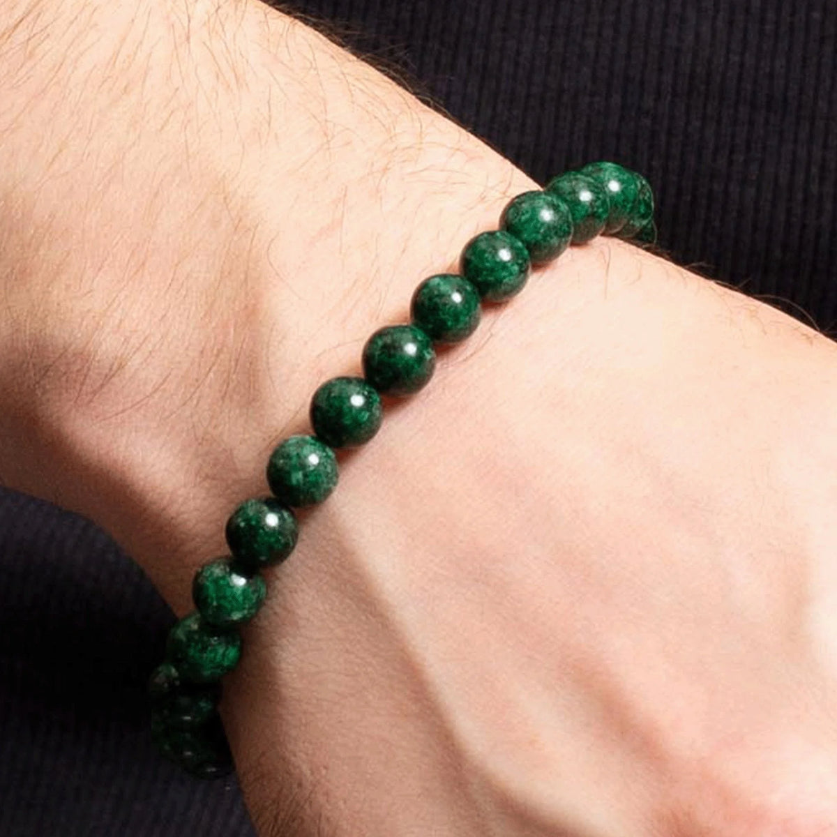 Green gemstone bead bracelet worn on a wrist.