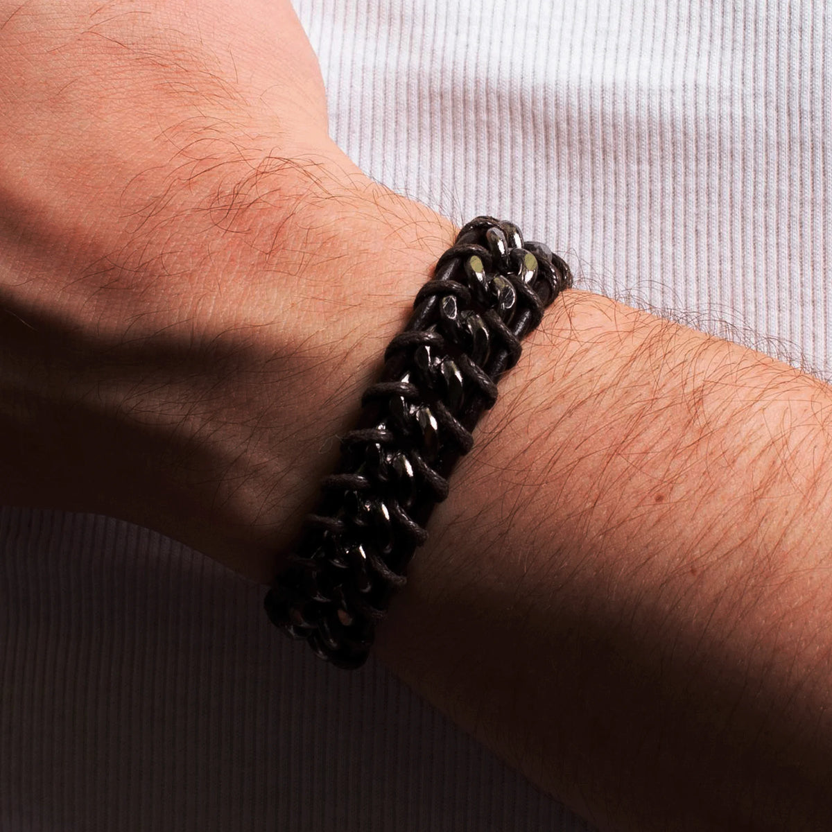 Black chain-link bracelet worn on a hairy wrist.