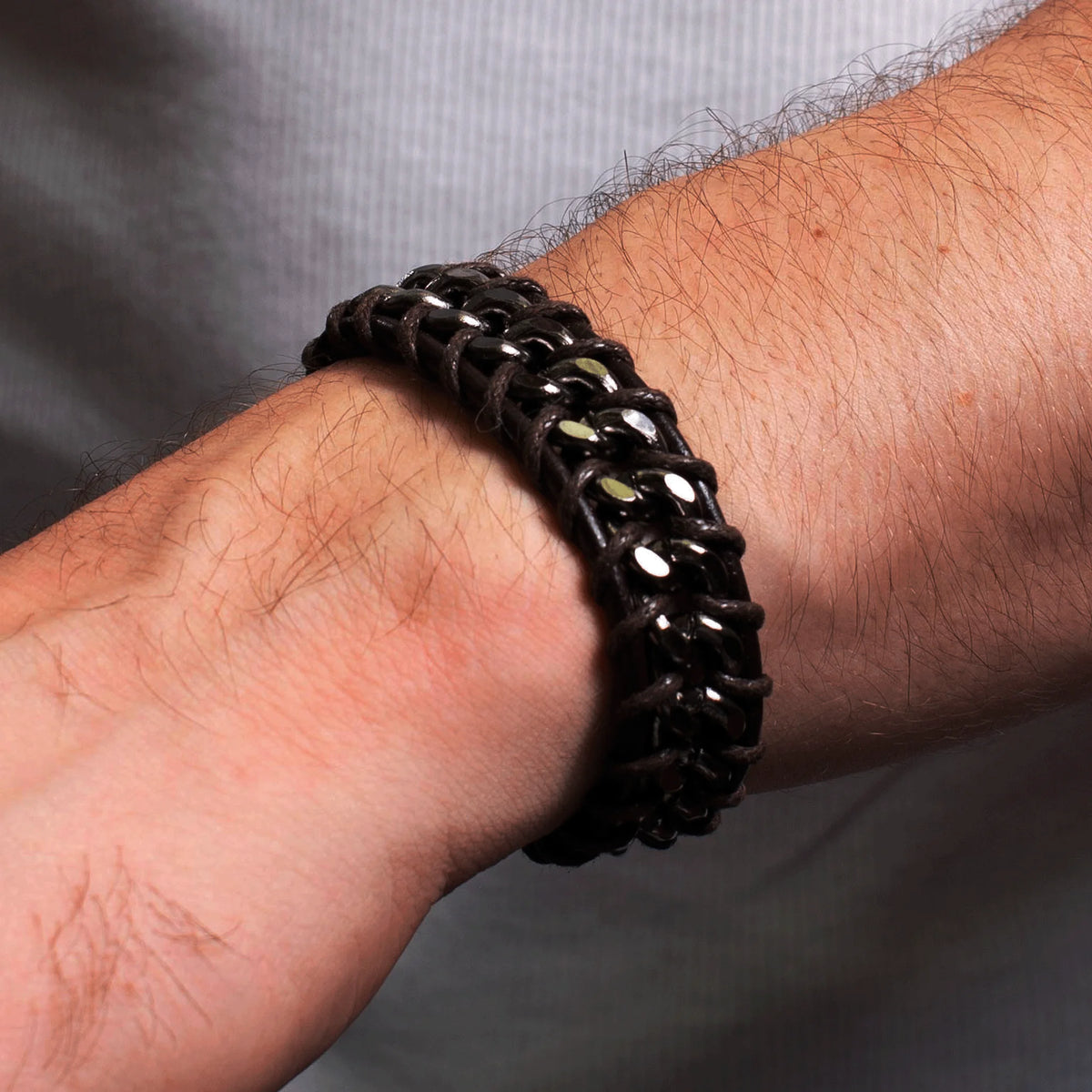 Black woven bracelet worn on a hairy wrist.