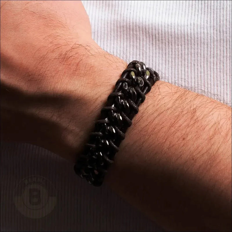 Black braided or chain-link bracelet worn on a wrist.