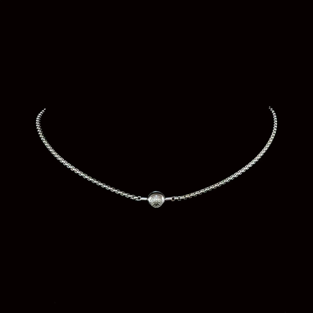 Delicate silver necklace with a single round diamond pendant.