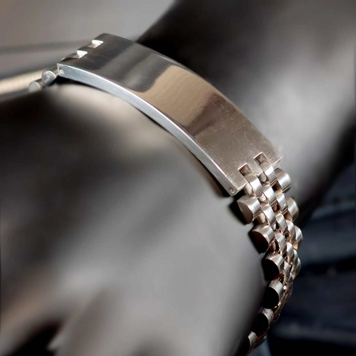 Metal watch bracelet with a polished finish and interlocking links.