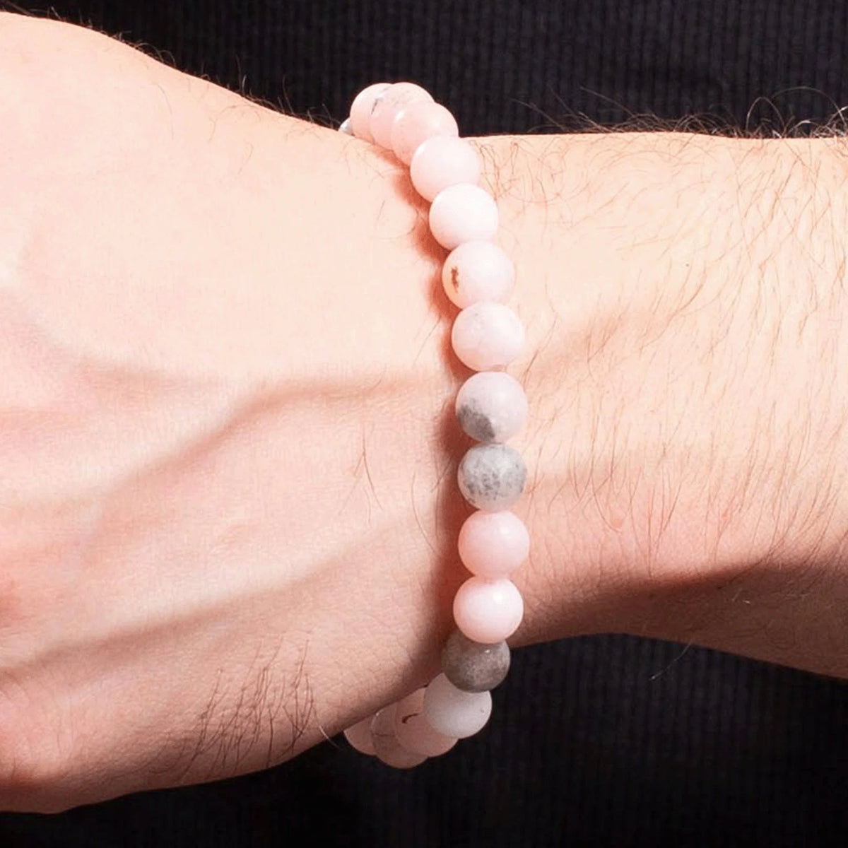 Beaded bracelet with pink and gray stones worn on a wrist.