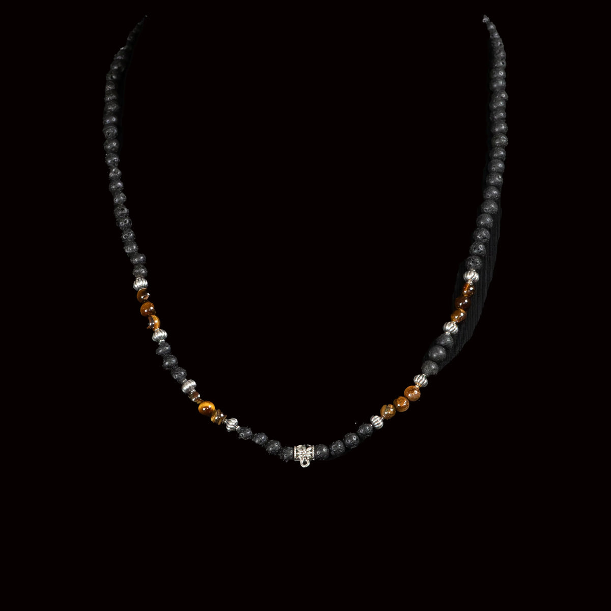 Beaded necklace with black, brown, and silver-colored beads on a dark background.