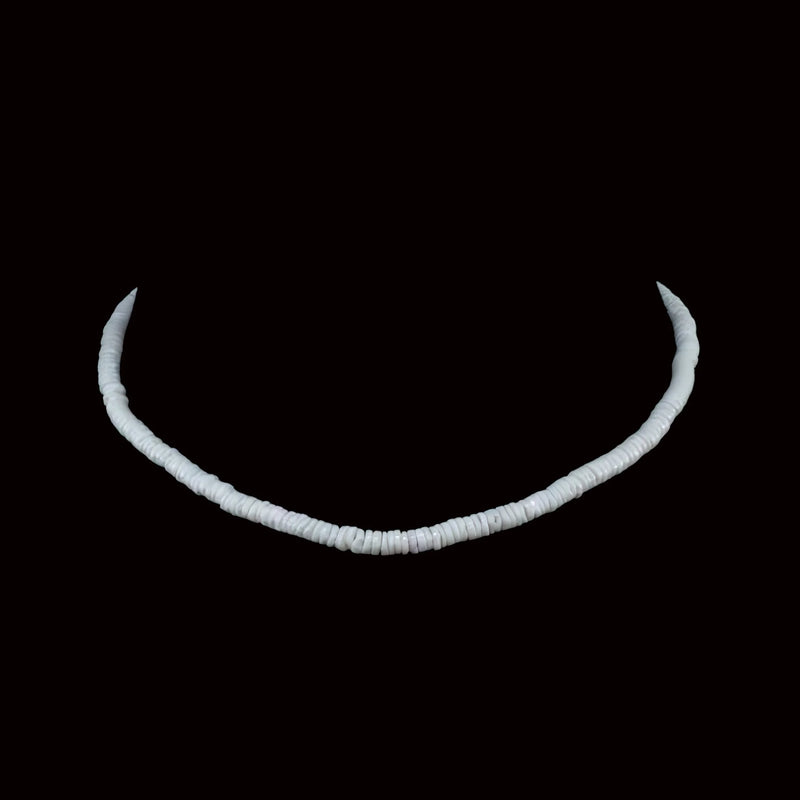 Curved white necklace made of small disc-shaped beads against a black background.