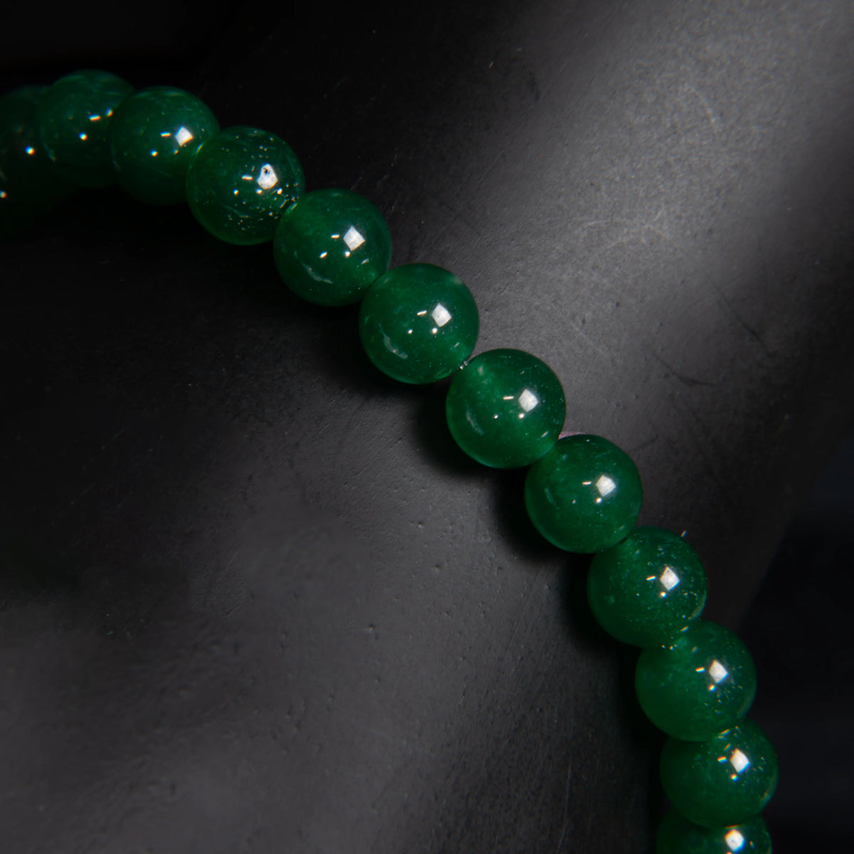 String of glossy dark green beads or gemstones.