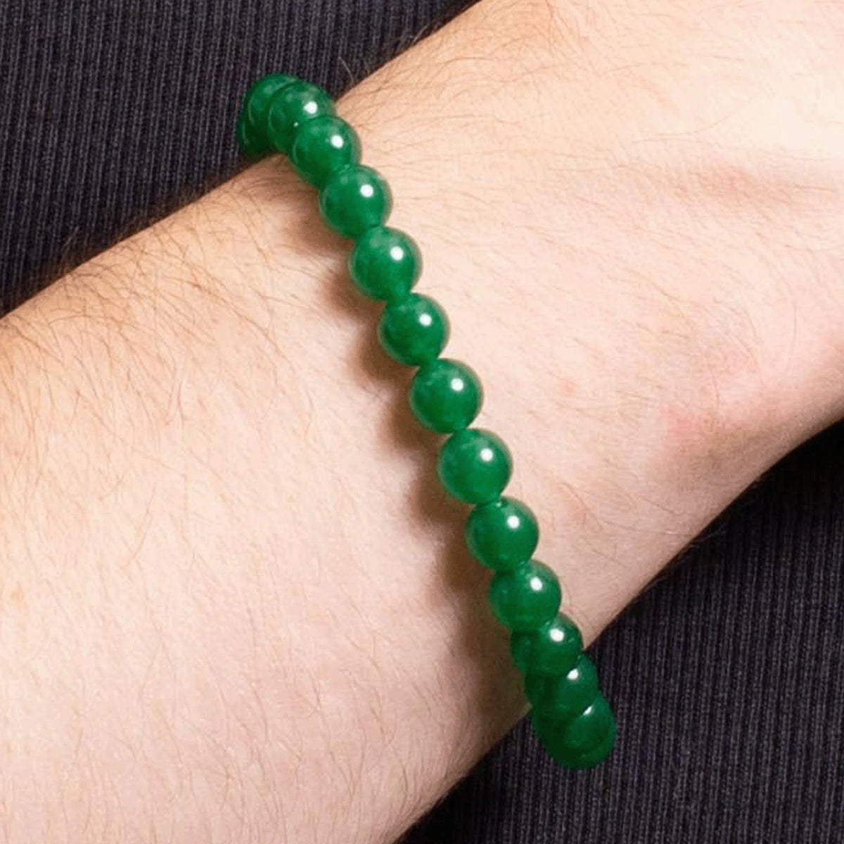 Green jade or gemstone bead bracelet worn on a wrist.