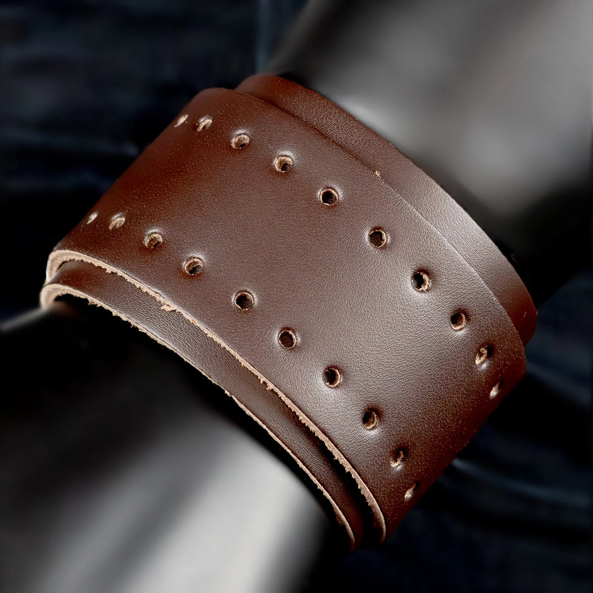 Brown leather cuff bracelet with perforated holes.