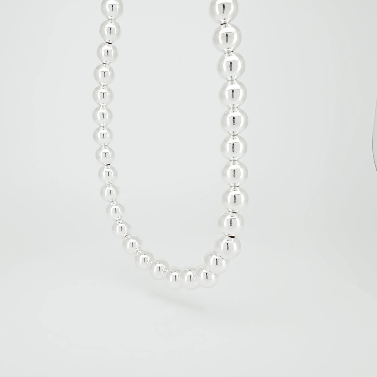 Silver bead necklace with spherical beads strung together.