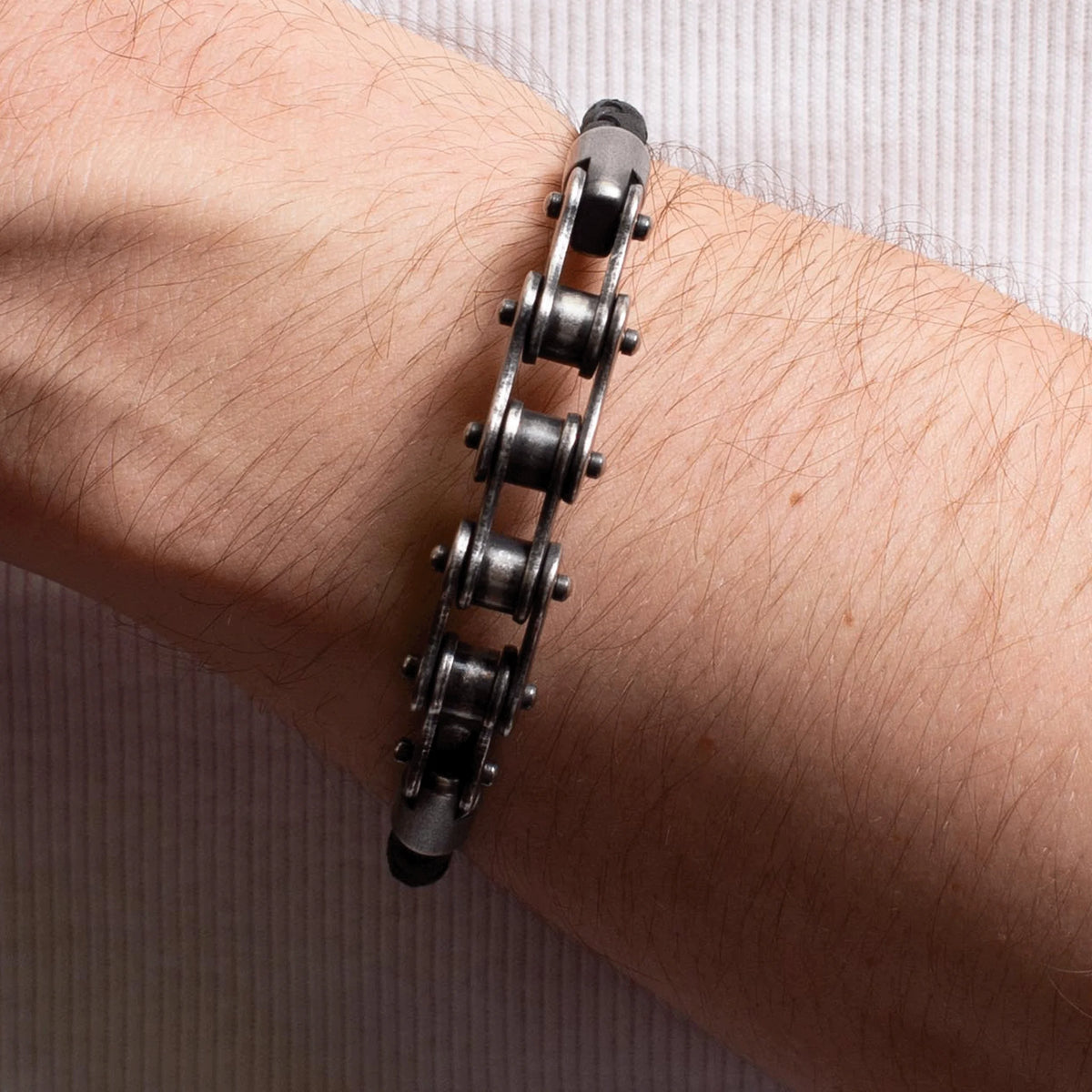 Metallic bracelet made from bicycle chain links worn on a wrist.