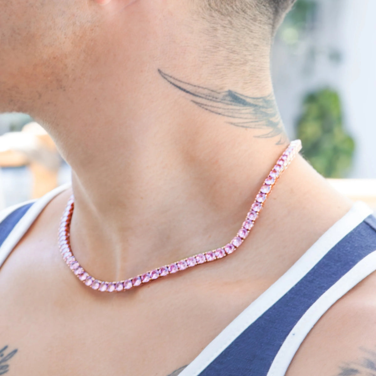 Pink gemstone or crystal necklace worn around a person’s neck.