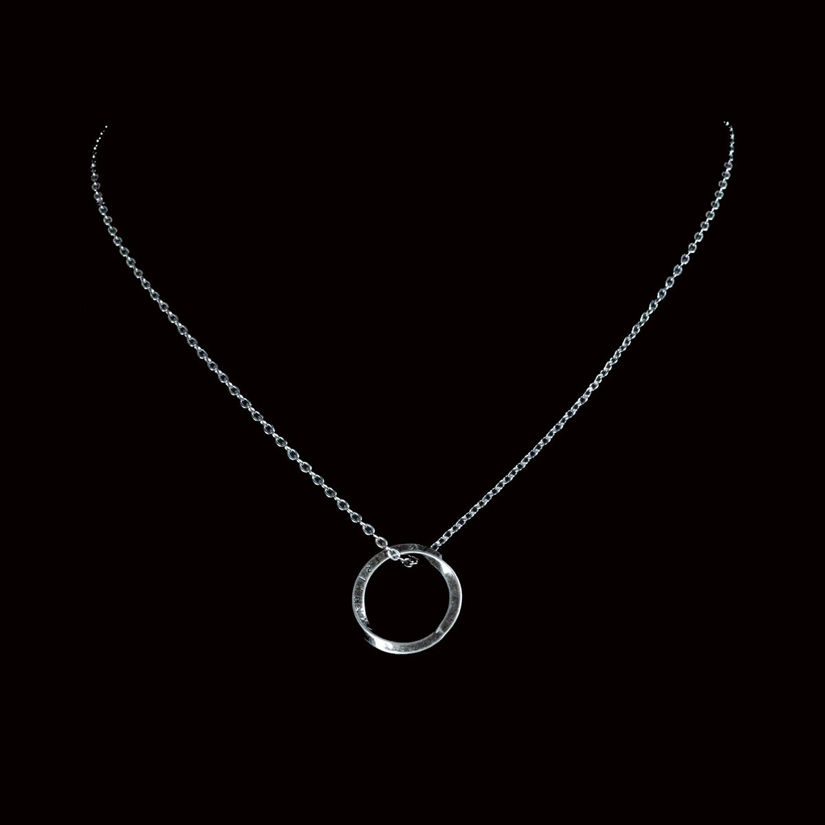 Silver necklace with a circular pendant.