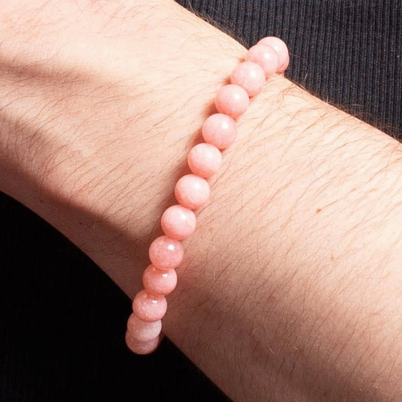 Pink coral or rose quartz beaded bracelet worn on a wrist.